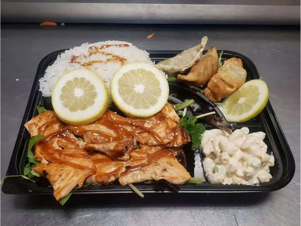 Luv-Ramen-&-BBQ-Japanese-restaurant-Salmon-Bento-Box-Hawthorne Bento box with grilled salmon, white rice, potstickers, macaroni salad, and lemon slices at Luv Ramen & BBQ, a Japanese restaurant in Hawthorne