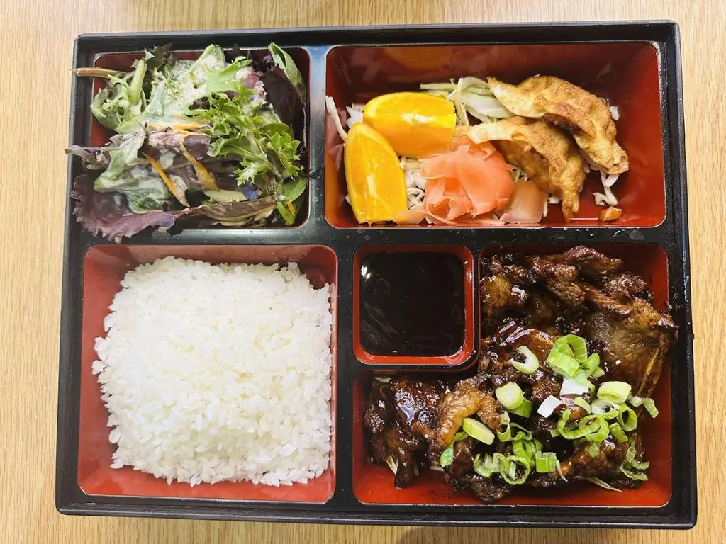 Luv-Ramen-&-BBQ-Japanese-restaurant-Teriyaki-Chicken-Bento-Hawthorne Bento with teriyaki chicken, white rice, mixed greens salad, orange slices, and potstickers at Luv Ramen & BBQ, a Japanese restaurant in Hawthorne